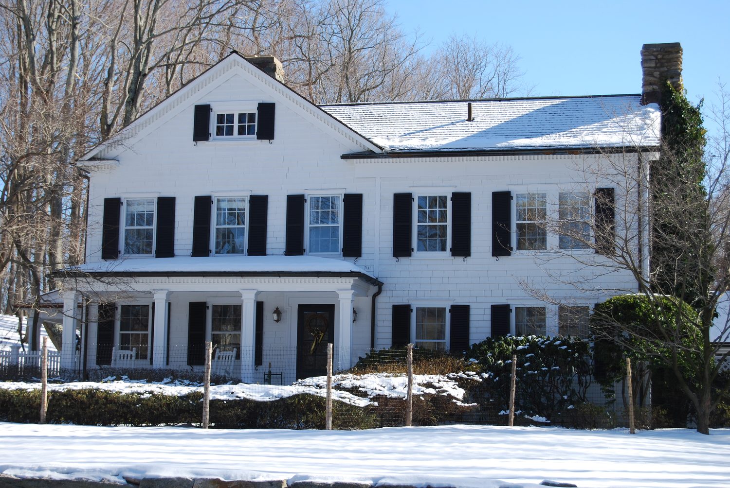 The house from the road, black shutters and a columned porch