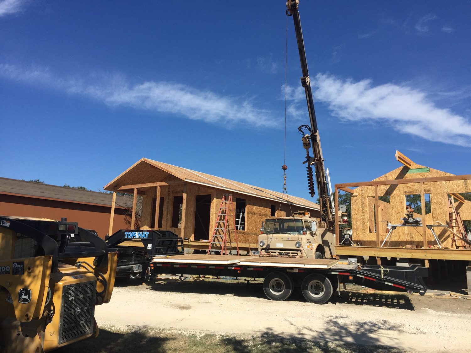 Several cabins under construction at once, with a crane and panel delivery
